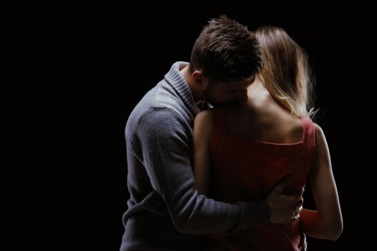 Мужчина целует женщину в шею